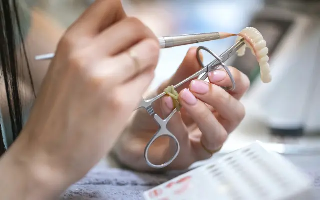 Dental technician finishing a dental bridge with fine instruments