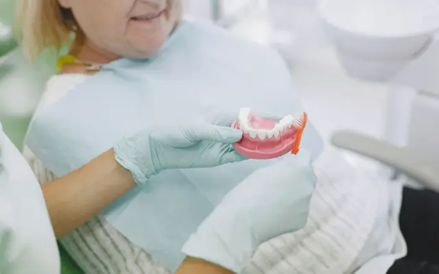Dentist showing a complete denture to a senior patient in the dental chair