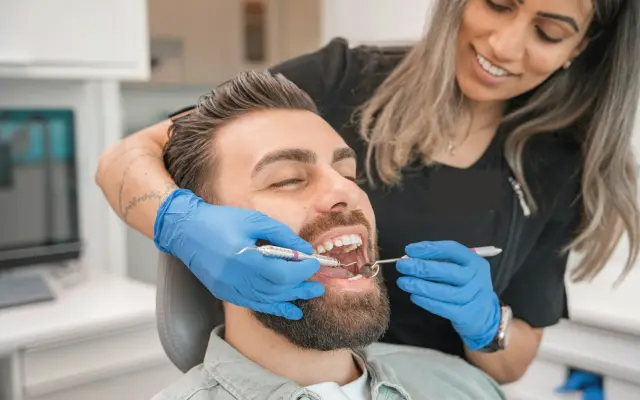 Dentist examining the teeth and gums of a smiling patient